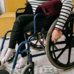 Person sitting in a wheelchair indoors wearing a striped shirt