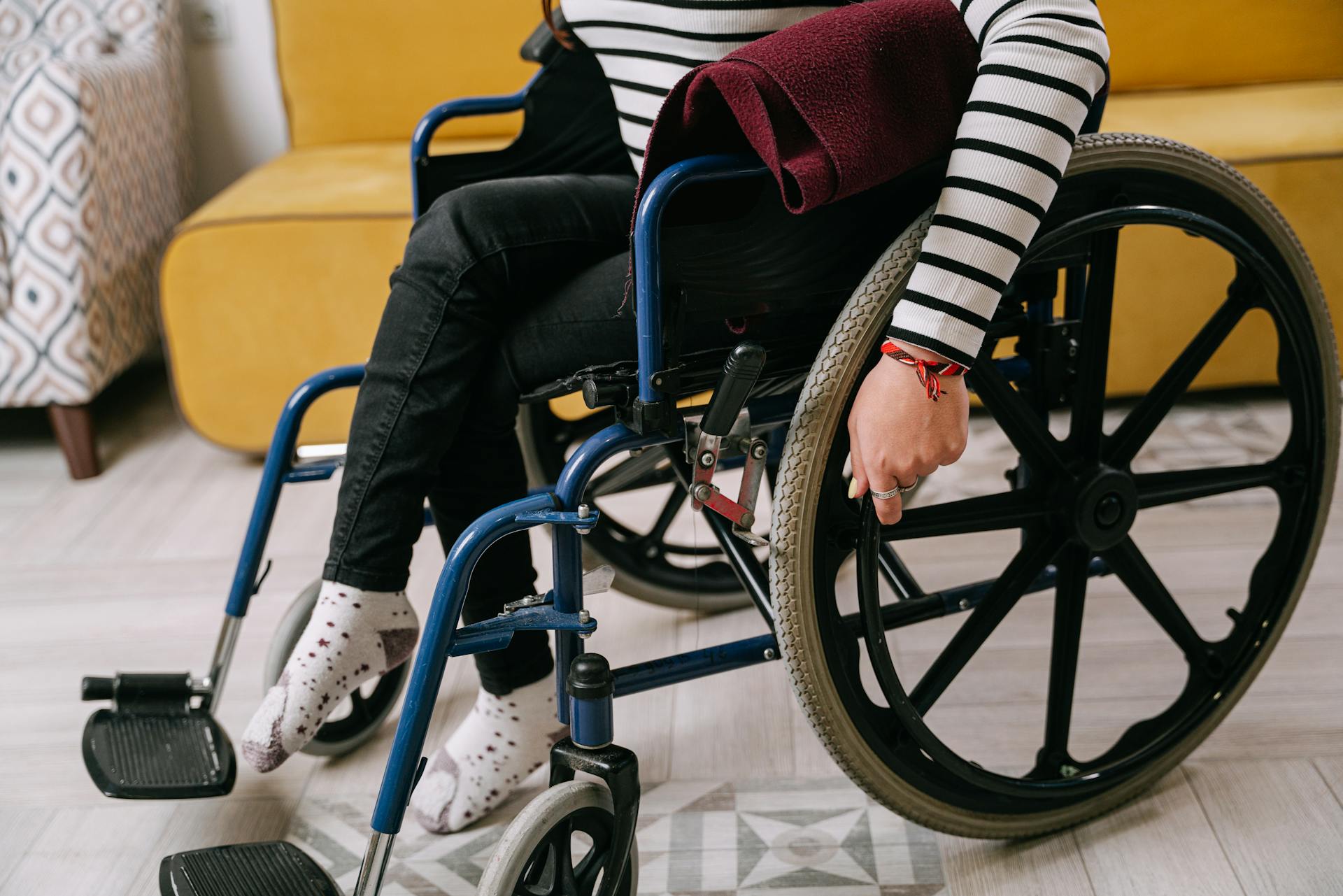 Person sitting in a wheelchair indoors wearing a striped shirt