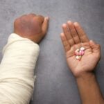 injured painful hand with bandage and medical pills on hand