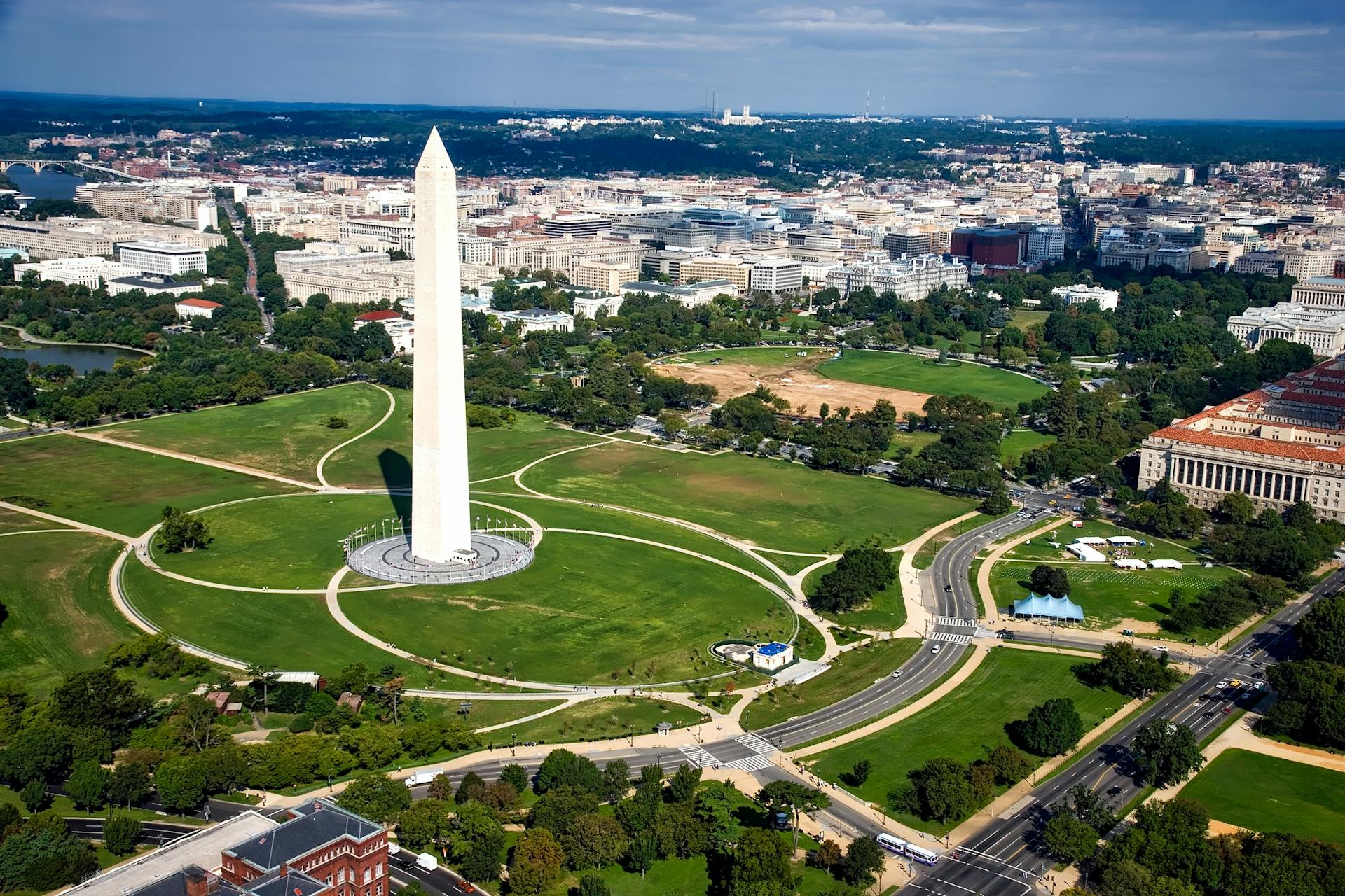A breathtaking aerial view of the Washington Monument surrounded by cityscape and green landscapes