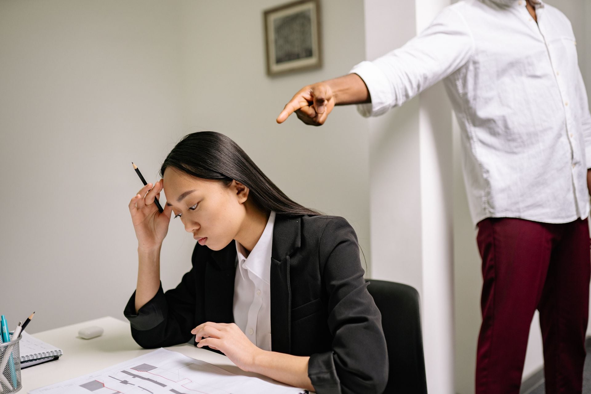 An office scenario depicting a young woman experiencing bullying from a coworker