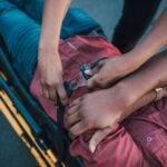 Close-up of a person securing an injured individual on a stretcher, providing emergency care.