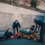 Emergency team helps an injured person on the street with a stretcher nearby