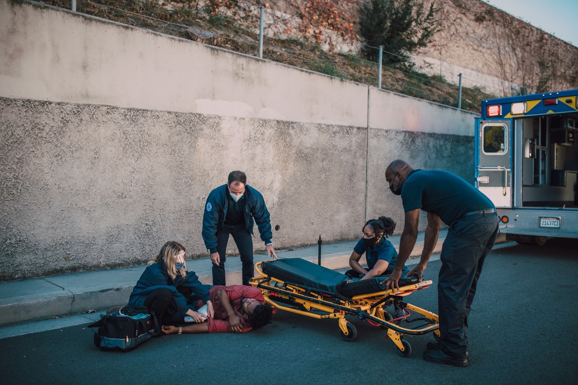 Emergency team helps an injured person on the street with a stretcher nearby