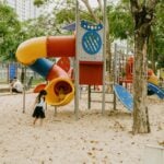Kids enjoying colorful slides and play structures in an outdoor park playground