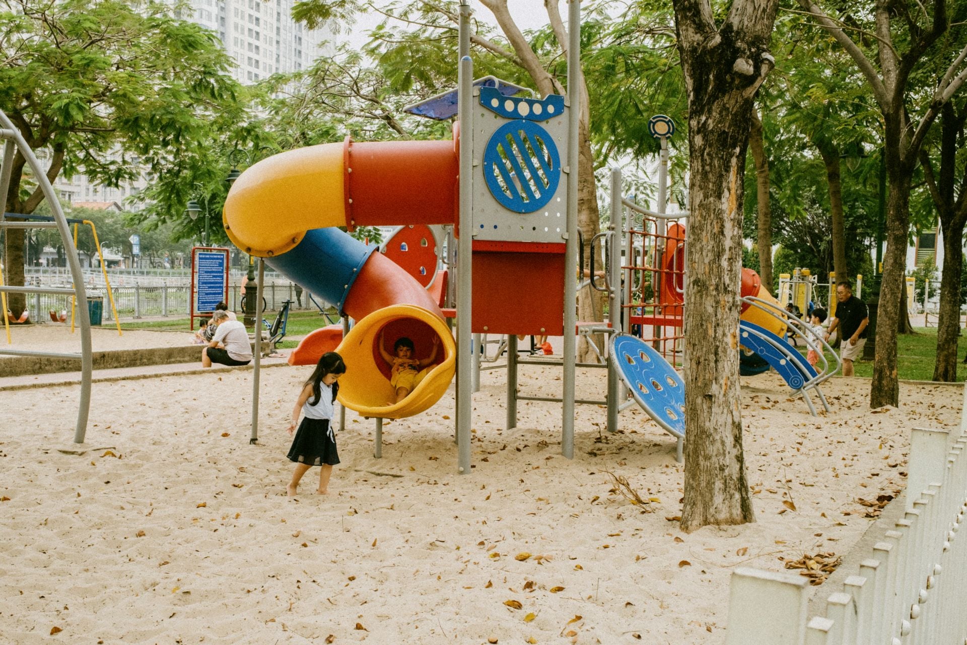 Kids enjoying colorful slides and play structures in an outdoor park playground