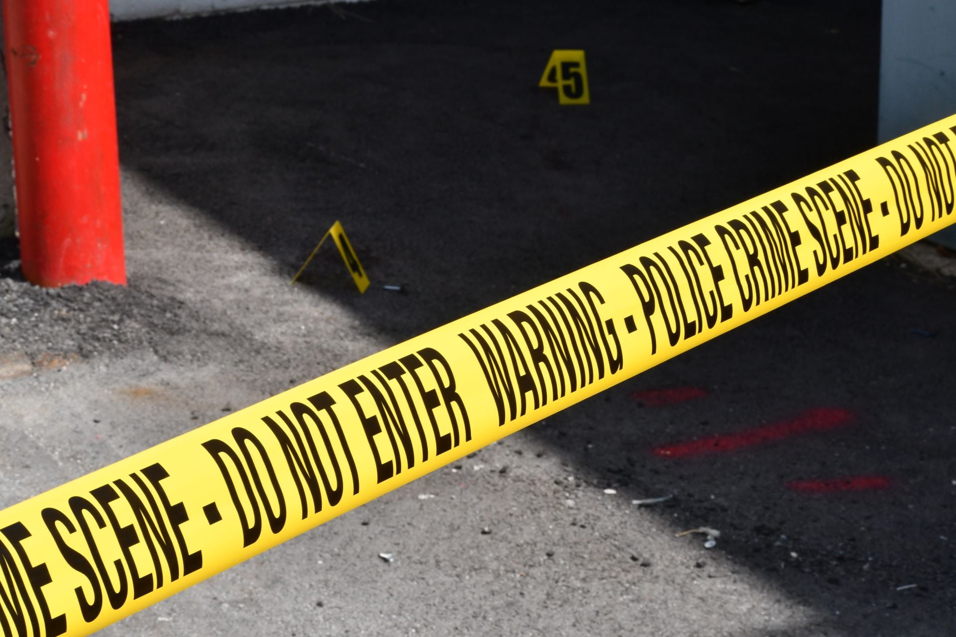 Yellow police crime scene tape marking a restricted urban area on concrete ground