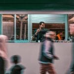 Why Understanding Buyer Motivation Is a Competitive Edge for Small Businesses 7 A street vendor serving customers through a kiosk window while people walk by in a busy market setting