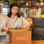 From Unfair Firing to Legal Claim: What Wrongful Termination Lawyers Look for in Your Case 8 An Asian woman packs a box labeled 'FIRED'