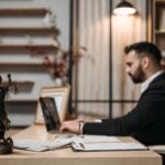 Why Expert Witness Consulting Firms Matter in Modern Litigation 7 Lawyer working diligently on a laptop in a modern office, Lady Justice statute present