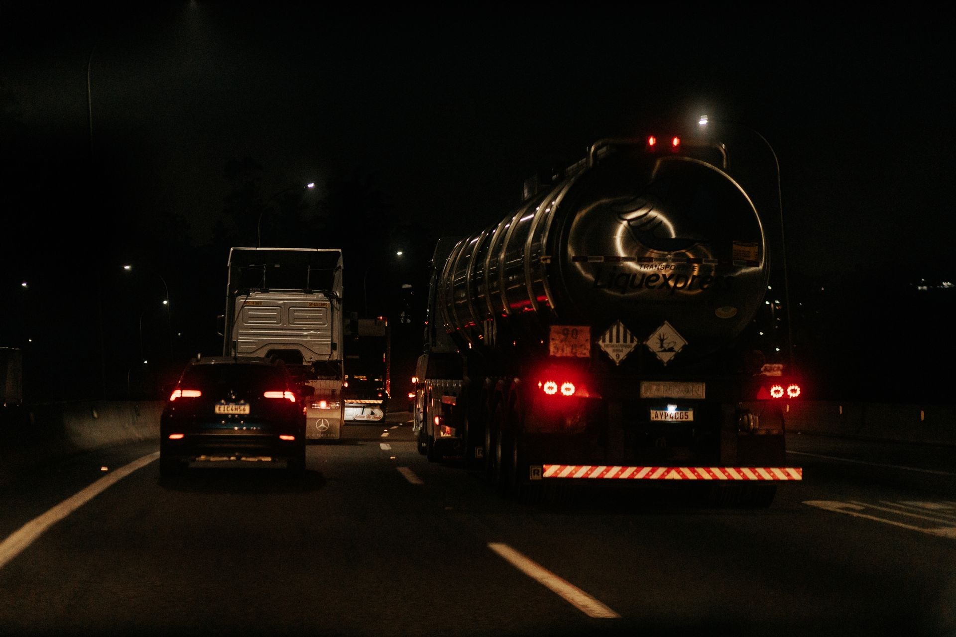 Vehicles drive down a dark highway at night, showcasing traffic and car lights