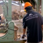 Workers wearing protective gear operating machinery in a factory environment, focusing on safety and production
