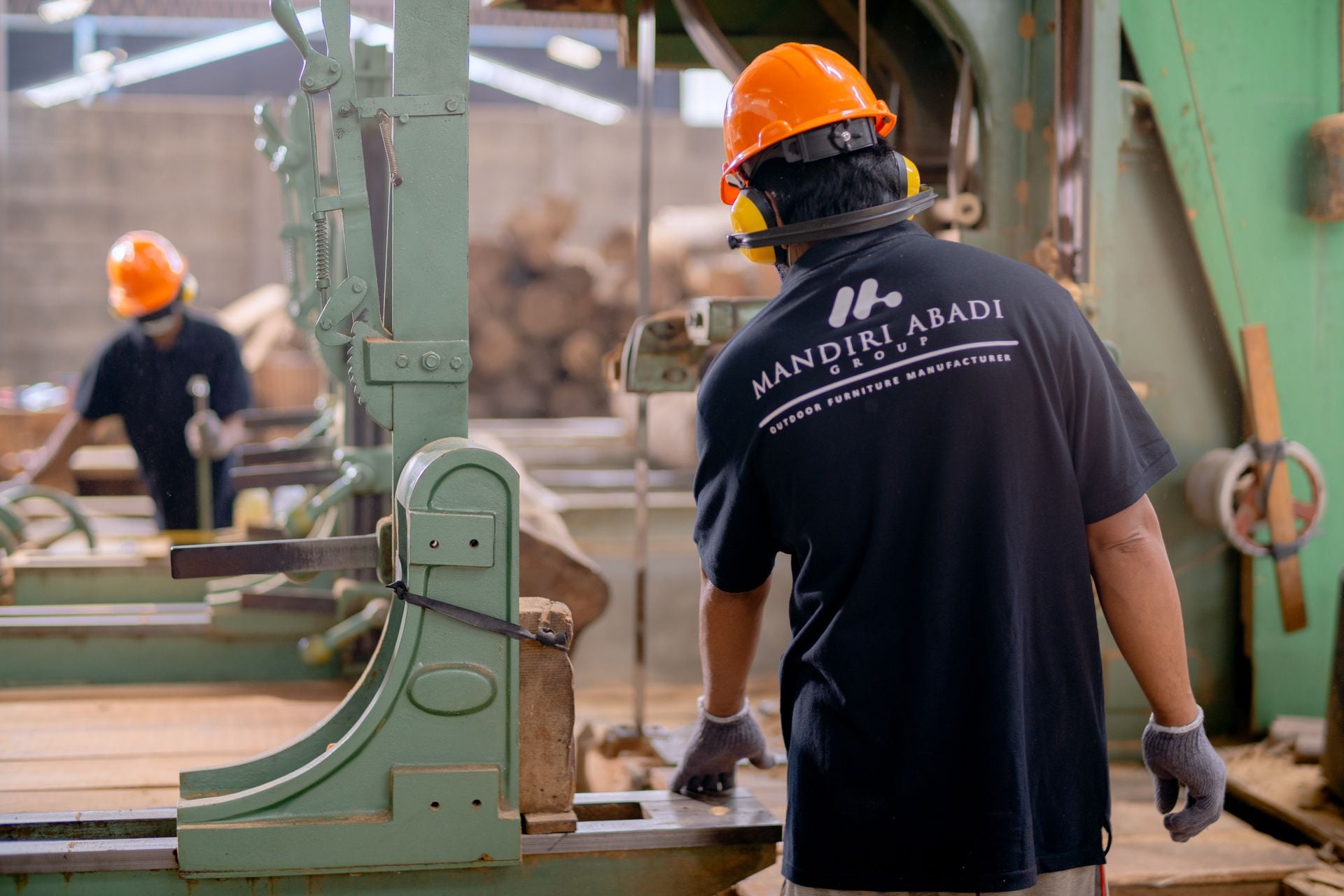 Workers wearing protective gear operating machinery in a factory environment, focusing on safety and production