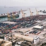 How Global Trade Laws Are Transforming Modern Trade Management Practices 7 Expansive aerial view of a bustling container port with large cranes and cargo ships under a cloudy sky