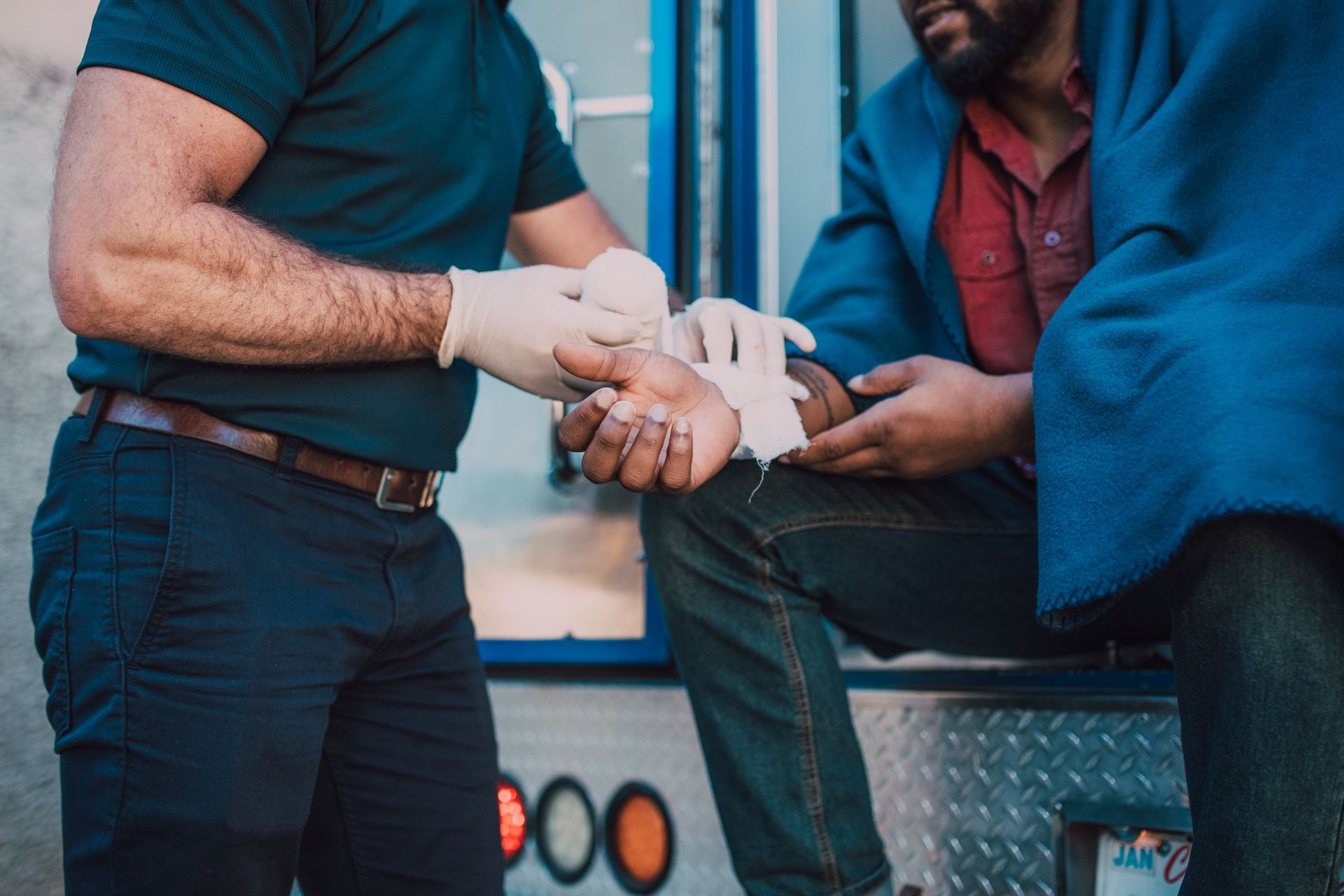 Paramedic offers first aid to an injured person near an ambulance