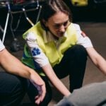 Two paramedics attend to a patient on the ground, providing emergency medical assistance