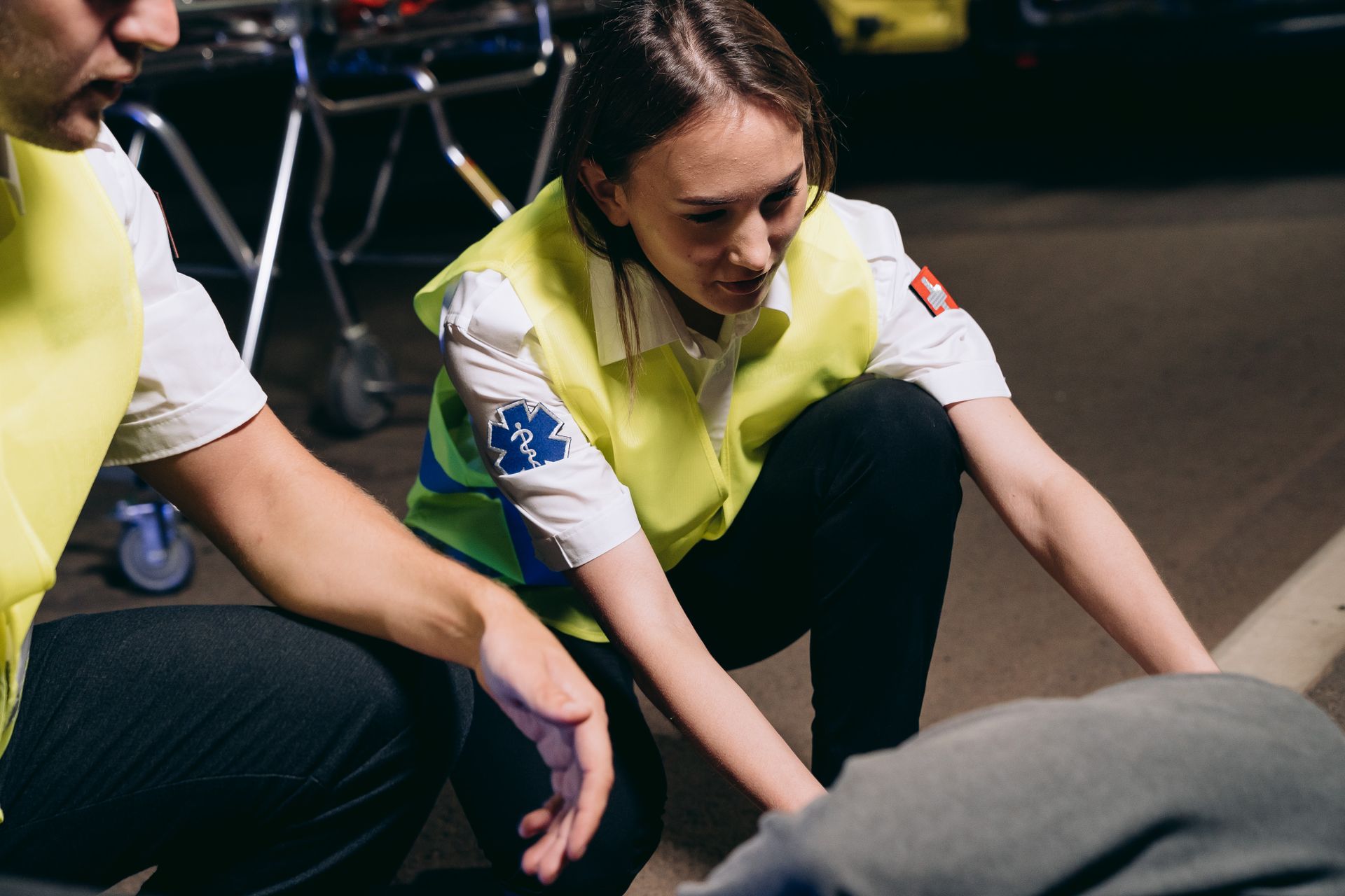 Two paramedics attend to a patient on the ground, providing emergency medical assistance