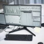 How Agentic AI is Reshaping People Analytics 7 A professional workspace featuring computers and analytical graphs on a monitor, symbolizing modern business environment