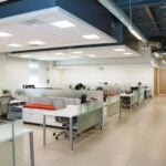 An open plan office with rows of white desks and frosted glass partitions
