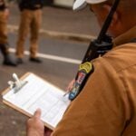 Close-up of a police officer writing on a clipboard outdoors in Londrina, Brazil.