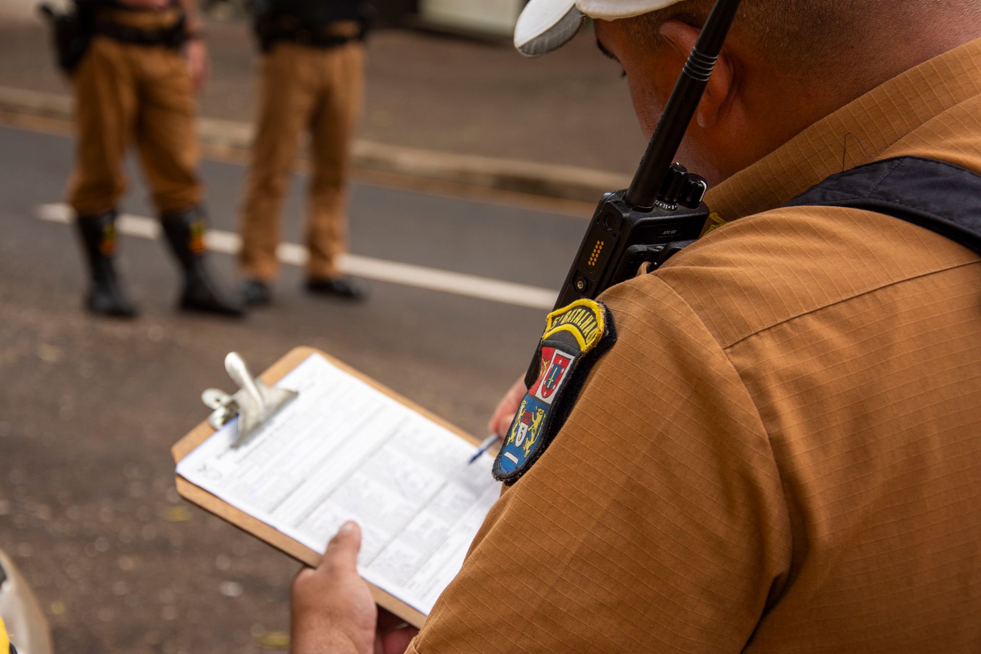 Close-up of a police officer writing on a clipboard outdoors in Londrina, Brazil.