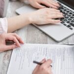 10 Questions Every HR Team Should Ask Before Choosing a Health Plan 15 Close-up of hands typing on a laptop and reviewing business documents, focused on finance and legal tasks