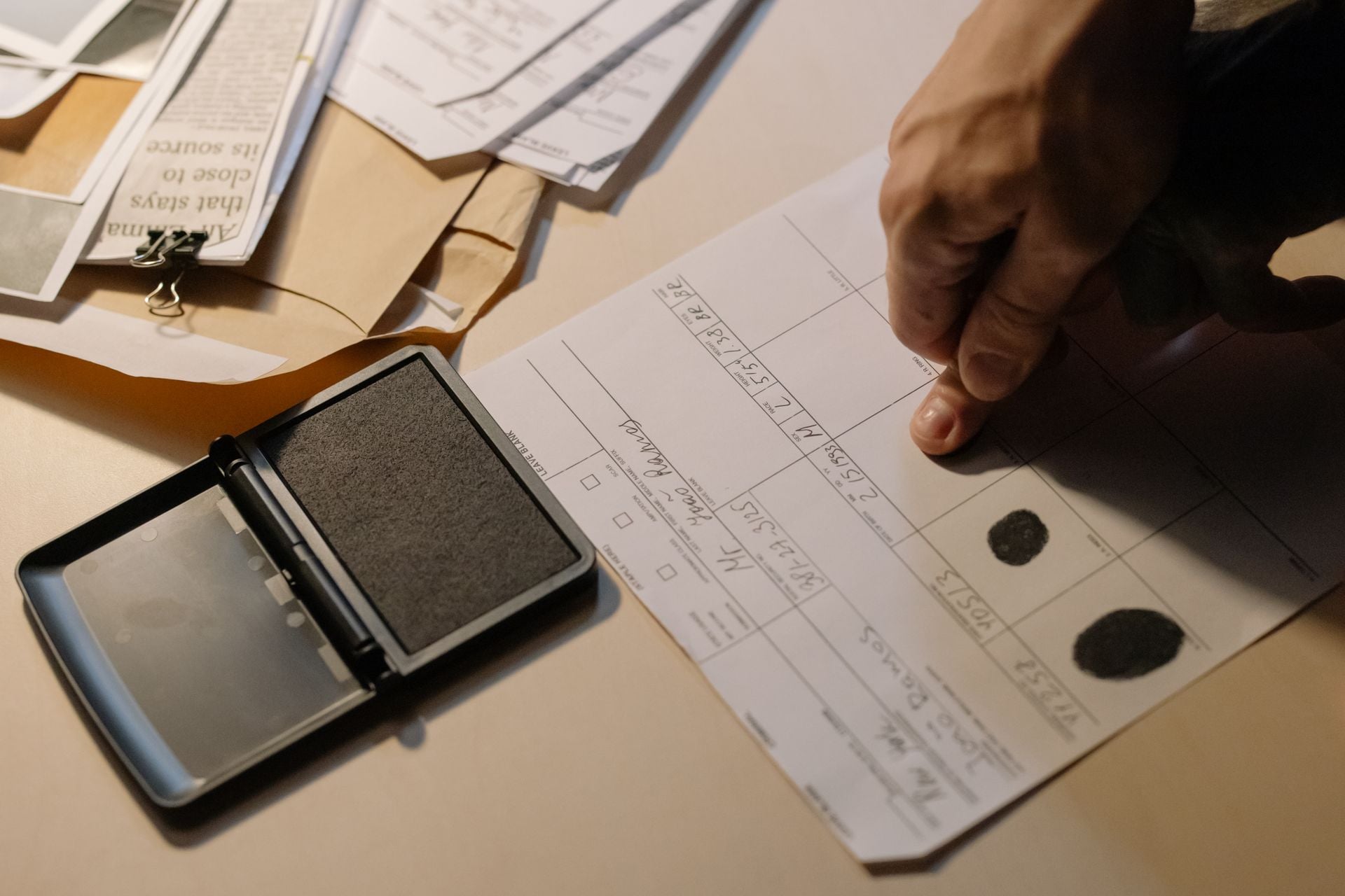 Detailed view of a hand taking fingerprints on a document with ink pad on desk