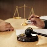 People talking in front of a gavel withe the scales of justice in the background