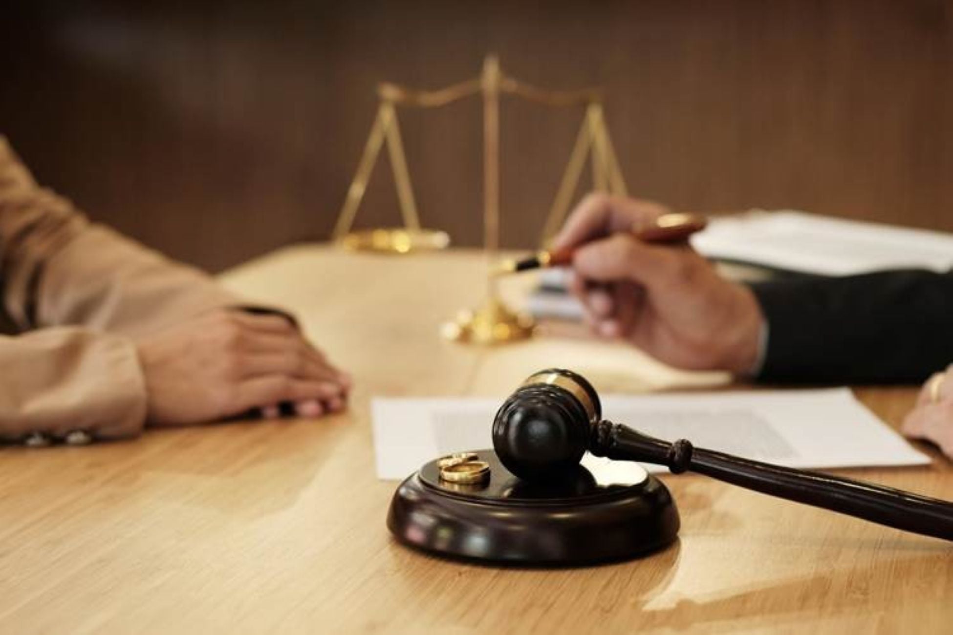 People talking in front of a gavel withe the scales of justice in the background