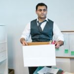 How Canadian Employment Law Protects Employees From Wrongful Dismissal 8 Professional man organizing office belongings in a cardboard box, preparing for transition