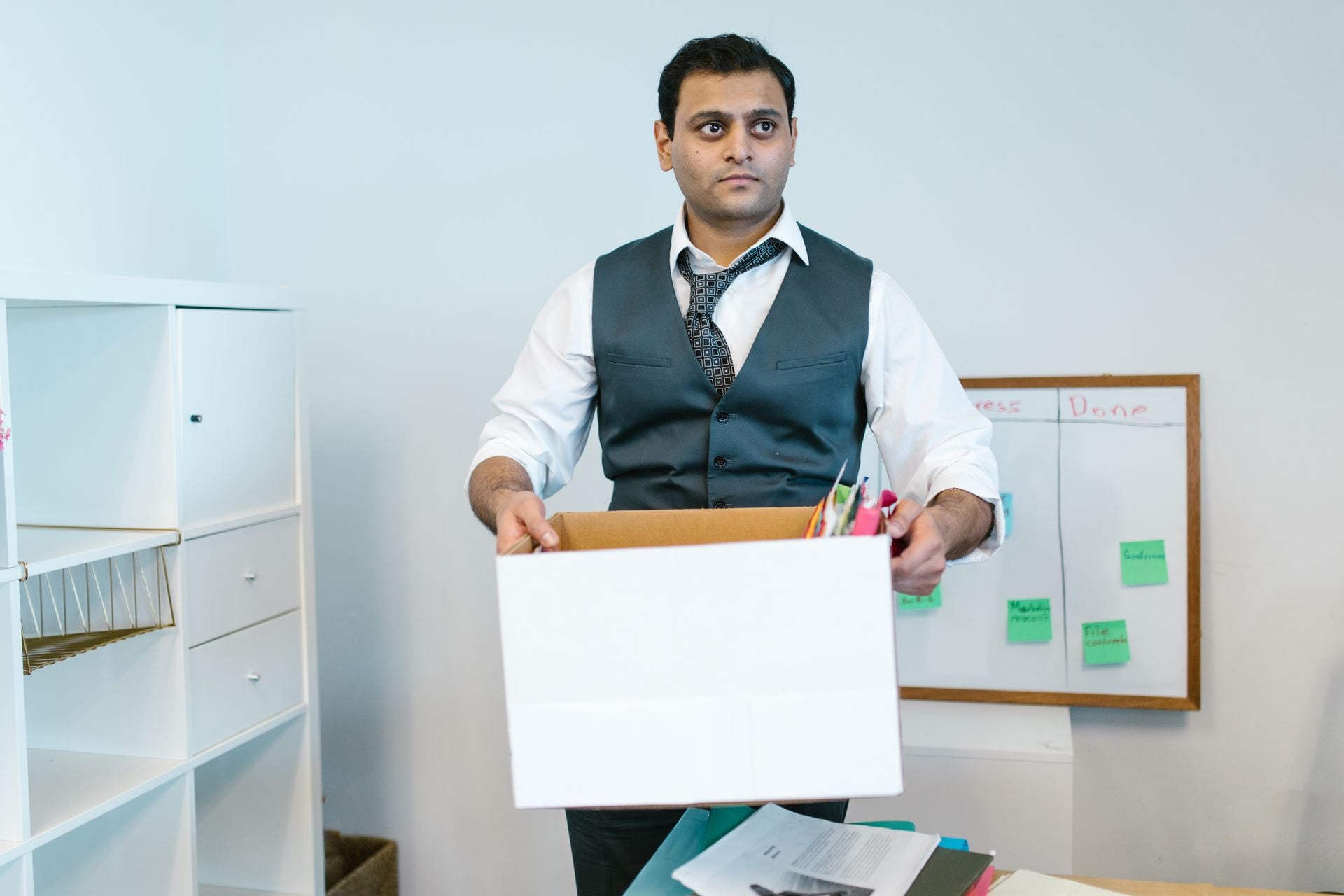 Professional man organizing office belongings in a cardboard box, preparing for transition