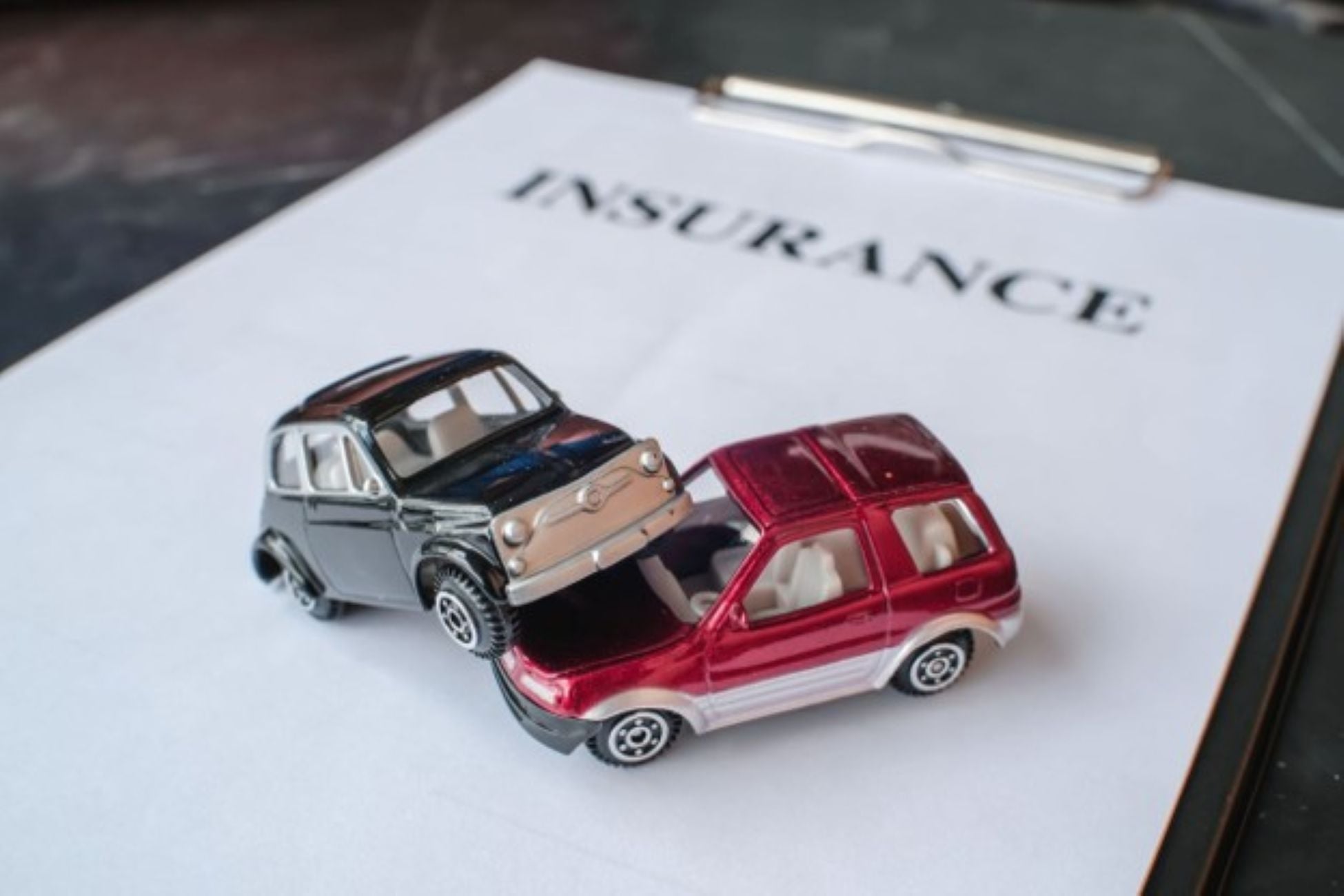 Toy car in an accident with insurance written in the background