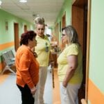 How to Spot and Document Warning Signs of Nursing Home Neglect 7 Two nurses interacting with a senior in a brightly colored care facility hallway