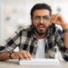 Guessing Game 8 Confused middle-eastern man programmer sitting at worktable