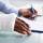 Overhead View Of Injured Man With Bandage Hand Filling Insurance Form