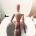 Guessing Game 7 brown wooden mannequin on white ceramic toilet bowl