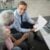 Retiring at 60? Here’s the Income Gap Most People Don’t Plan For 7 An Agent Showing Documents to an Elderly Man