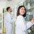Happy asian pharmacist in white coat writing on clipboard