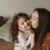 A tender moment of a mother kissing her smiling daughter indoors