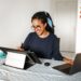 Guessing Game 4 A young woman smiling while working on a laptop and drawing tablet at home